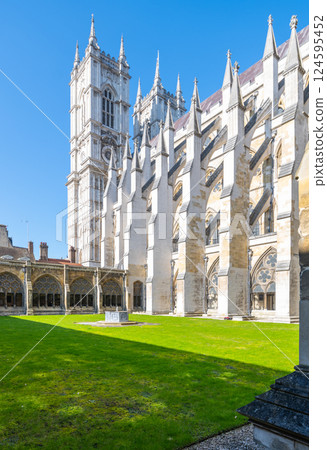 Visitors enjoy the serene green lawn at the Cloisters of Westminster Abbey in London, surrounded by stunning Gothic architecture under a clear blue sky. Visitors enjoy the serene green lawn at the Cloisters of Westminster Abbey in London, surrounded by stunning Gothic architecture under a clear blue sky. 124595452