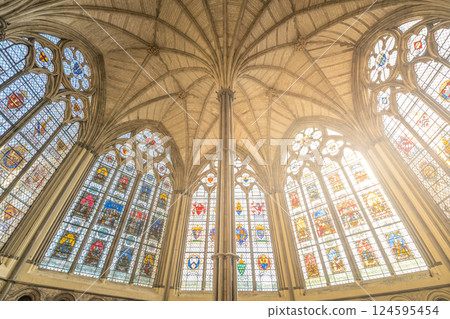 A view captures the intricate stained glass windows and ornate ceiling of the Chapter House at Westminster Abbey, highlighting the historical architecture in London during daylight. 124595454