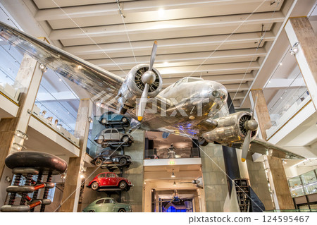 A historic Lockheed 10A Electra aircraft is showcased prominently at London's Science Museum. Vintage cars are positioned alongside, creating a fascinating travel exhibit. 124595467