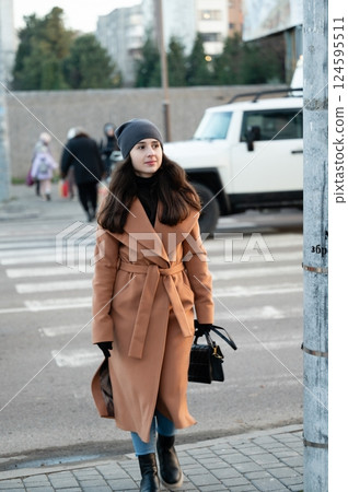 Taking a leisurely stroll through the vibrant city streets on a crisp, chilly day, I am dressed in a stylish coat and carrying an elegant handbag, all while soaking in the lively atmosphere around me Taking a leisurely stroll through the vibrant city streets on a crisp, chilly day, I am dressed in a stylish coat and carrying an elegant handbag, all while soaking in the lively atmosphere around me 124595511