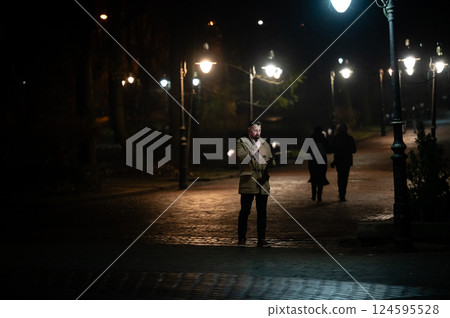 Strolling through the charming park under the warm glow of street lamps during a quiet evening filled with whispers and laughter 124595528