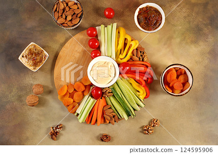 Healthy food kitchen background with hummus bowl and raw vegetable sticks, nuts and dried apricots. Hummus platter with appetizers, Middle Eastern plate, traditional vegan snacks, oriental cuisine Healthy food kitchen background with hummus bowl and raw vegetable sticks, nuts and dried apricots. Hummus platter with appetizers, Middle Eastern plate, traditional vegan snacks, oriental cuisine 124595906