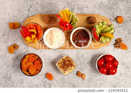 Oriental cuisine and healthy snack concept, Healthy food kitchen background with hummus bowl and raw vegetable sticks, nuts and dried apricots. Hummus platter with appetizers, traditional vegan 124595912