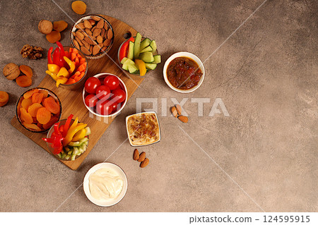 Healthy food kitchen background with hummus bowl and raw vegetable sticks, nuts and dried apricots. Hummus platter with appetizers, Middle Eastern plate, traditional vegan snacks, oriental cuisine 124595915