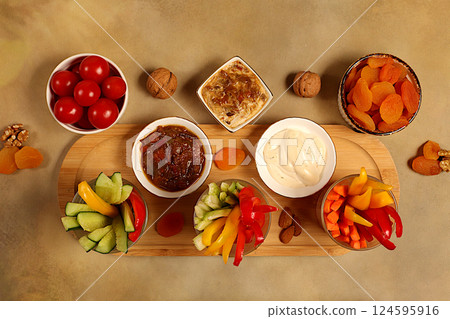 Hummus platter with appetizers, healthy food kitchen background with hummus bowl and raw vegetable sticks, nuts and dried apricots. Middle East plate, traditional vegan appetizers, oriental cuisine 124595916