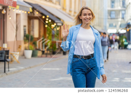 Woman tourist smiling friendly at camera waving hands gesturing invitation hello hi greeting goodbye Woman tourist smiling friendly at camera waving hands gesturing invitation hello hi greeting goodbye 124596268