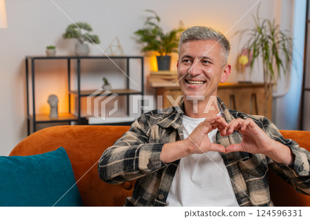 Smiling man at home makes symbol of love showing heart sign to camera express romantic feelings 124596331