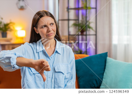 Upset unhappy young woman showing thumbs down sign dislike gesture disapproval bad work feedback 124596349