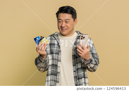 Asian man using credit bank cards smartphone transferring spending money purchases online shopping 124596413