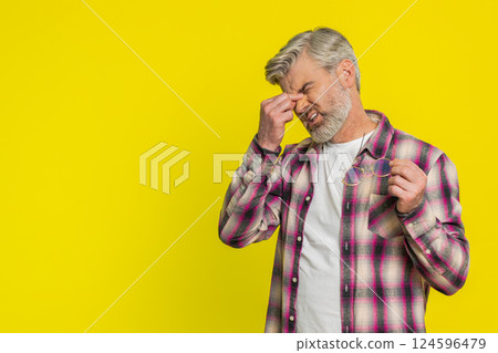 Mature man removing glasses, tired eyes discomfort, post-work fatigue sign, subtle strain expression 124596479