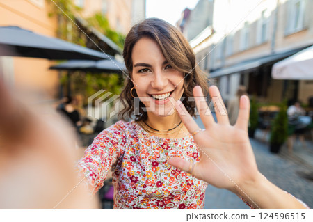 Young woman blogger taking selfie on smartphone video call online with subscribers in city street 124596515