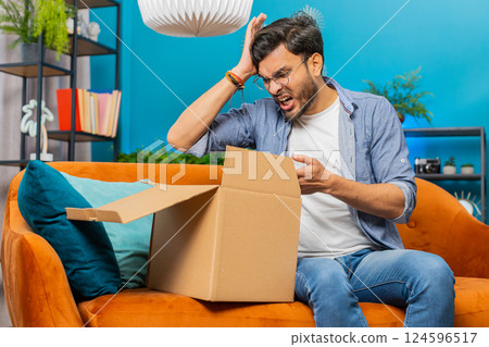 Angry dissatisfied shopper Indian man unpacking parcel feeling upset, confused, wrong delivery 124596517