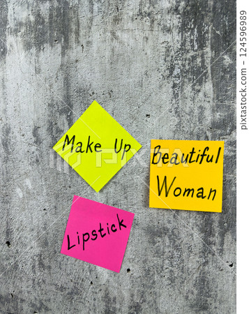 Vertical photo with conceptual idea of makeup for girl. Lipstick and cosmetics for decoration and attracting attention of stunning girl. Sticky notes with words about cosmetics on background 124596989