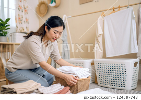 Woman Folding Laundry in a Cozy, Organized Laundry Room During Daylight Hours 124597748