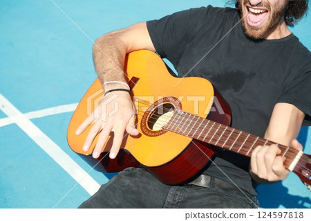 Long Hair Man Plays Classical Guitar Unleashed Outside In Blue Field Long Hair Man Plays Classical Guitar Unleashed Outside In Blue Field 124597818
