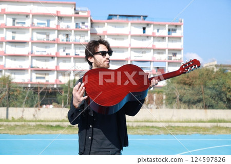 Acrobat With Classical Guitar Balancing On Foot For Street Art Show 124597826