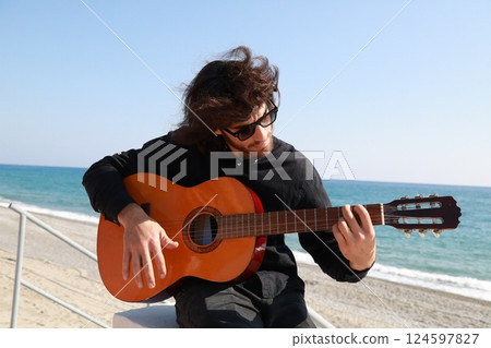 Man Plays Classical Guitar On The Beach Near The Sea In Summer 124597827