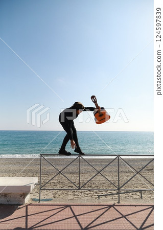 Guitar Musician Balancing On Railing Walks At Beach Near Ocean 124597839