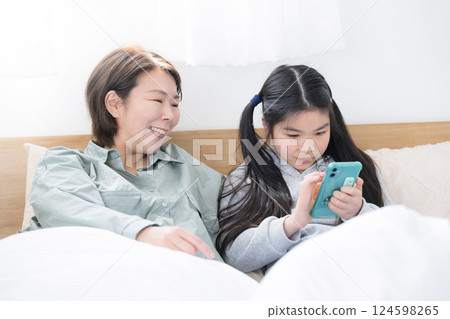 A mother watching over her elementary school child's smartphone A mother watching over her elementary school child's smartphone 124598265