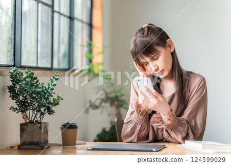 中年婦女在咖啡館使用智慧型手機（眼睛疲勞、智慧型手機老花眼、眼睛疲勞、頭痛） 124599029