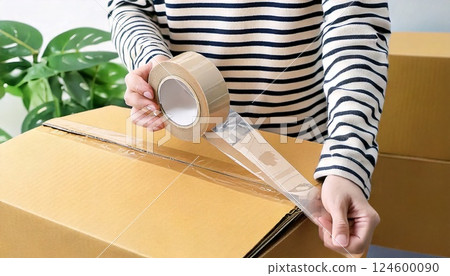一名準備搬家的女子正在用手將膠帶貼在紙箱上 124600090