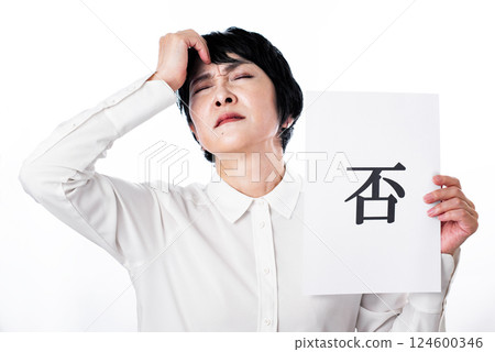 一名中年婦女錶情不悅，手裡拿著一張寫著「不」字的紙 124600346
