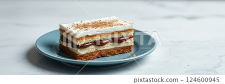 Delicious layered dessert served on a blue plate in a bright kitchen setting 124600945