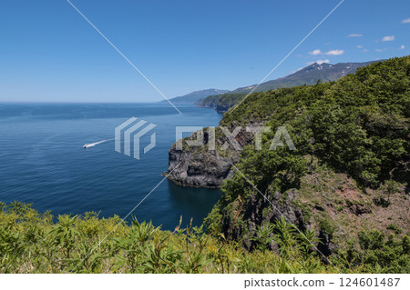A tourist boat heading to Cape Shiretoko in early summer and the Shiretoko mountain range A tourist boat heading to Cape Shiretoko in early summer and the Shiretoko mountain range 124601487