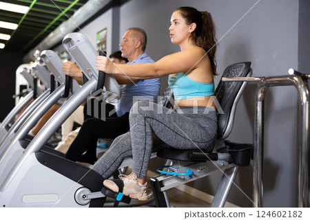 Young girl working out on stationary bicycle in gym Young girl working out on stationary bicycle in gym 124602182