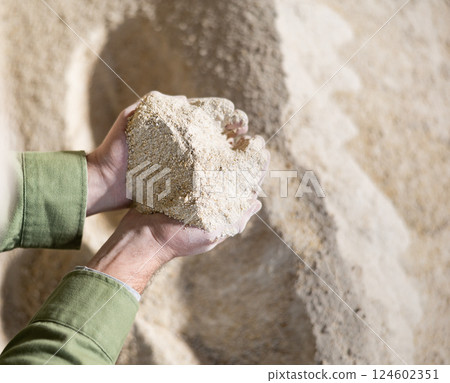 Farmer holds a handful of cornmeal in his hands - feed for cows and other animals on farm 124602351