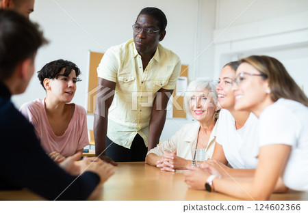 African american male teacher, together with students of different ages, conducts intensive classes at round table in university auditorium African american male teacher, together with students of different ages, conducts intensive classes at round table in university auditorium 124602366
