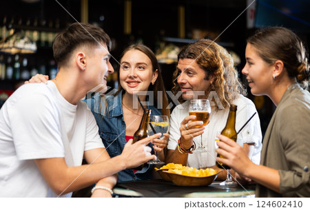 Company of friends drinking beer, eating chips and talking with each other in a pub Company of friends drinking beer, eating chips and talking with each other in a pub 124602410
