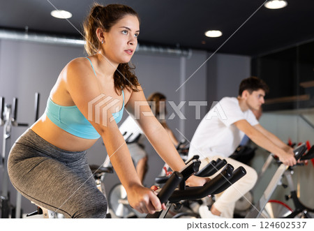 Young girl doing cardio training on stationary bike in gym 124602537
