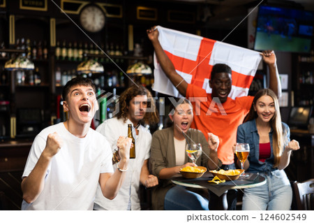 Excited guy emotionally cheering for team from England in sports bar Excited guy emotionally cheering for team from England in sports bar 124602549
