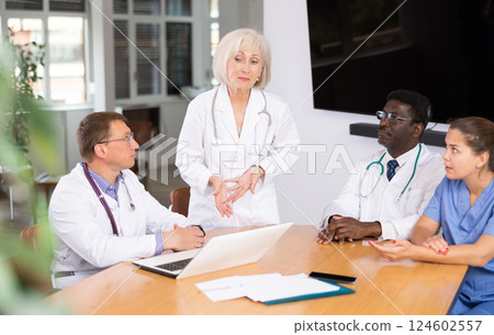 Mature female doctor speaks at meeting of colleagues and tells reports on condition of patients. Mature female doctor speaks at meeting of colleagues and tells reports on condition of patients. 124602557