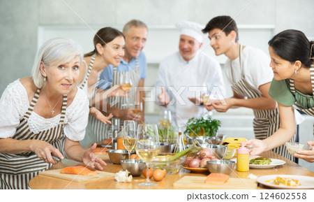 Smiling elderly woman engrossed in cooking at group culinary class 124602558