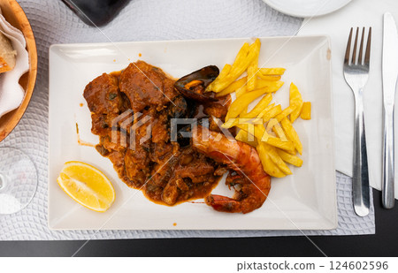 Hake in sailor style - fish cooked in thick tomato sauce with addition of mussels and shrimp Hake in sailor style - fish cooked in thick tomato sauce with addition of mussels and shrimp 124602596