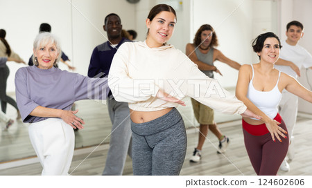 Smiling girl learning dynamic dances in group choreography class Smiling girl learning dynamic dances in group choreography class 124602606