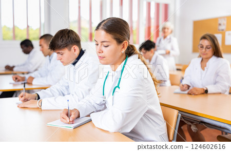 Young girl medical student taking notes during group lecture Young girl medical student taking notes during group lecture 124602616
