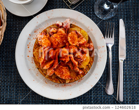 Chopped spicy boiled octopus tentacles with potato slices traditionally seasoned with aromatic paprika 124602618