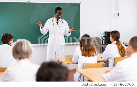 Positive professor speaking to group of students in medical college 124602700