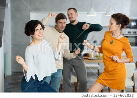 Friends dancing. Cheerful young people dancing and drinking while enjoying home party on room 124602828