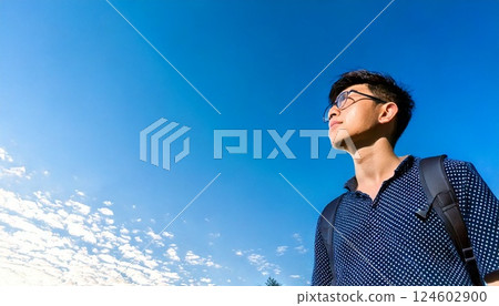 A teenage boy looking up at the blue sky A teenage boy looking up at the blue sky 124602900