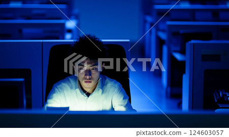 A man operating a PC in an office late at night 124603057