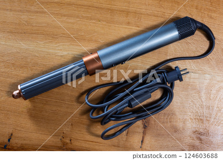 Hair styling tool for creating curls on wooden table Hair styling tool for creating curls on wooden table 124603688
