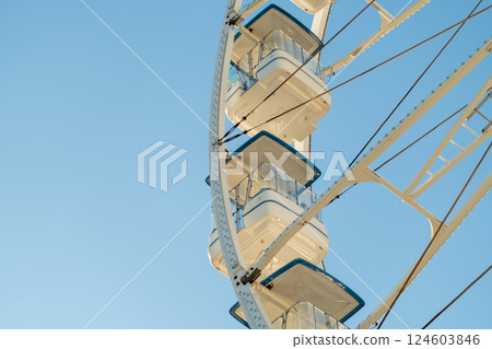 Ferris wheel with white gondolas at amusement park 124603846