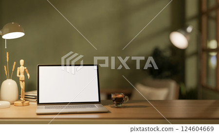 The white screen laptop and coffee cup place on wooden table with decor in the dim light green room. The white screen laptop and coffee cup place on wooden table with decor in the dim light green room. 124604669