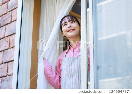 Housewife opening the window and looking outside Housewife opening the window and looking outside 124604787