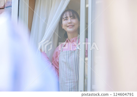 Housewife opening the window and looking outside Housewife opening the window and looking outside 124604791
