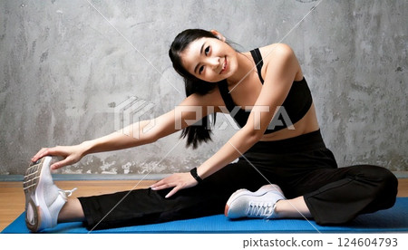 一名女子在瑜珈墊上伸展身體 124604793